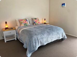 Ein Schlafzimmer mit einem Bett, zwei Nachttischlampen, einem Nachttisch mit Schublade und einem Wandbild.