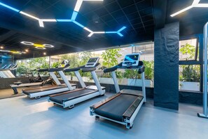 A gym with treadmills, exercise bikes, and a large window with plants. - Cozy 2 BR with Heater,Gym,Pool,ample parking on 3floors at Lavington,Nairobi (Nairobi)