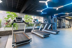 Ein Fitnessstudio mit Laufbändern, Kraftgeräten und einer Treppe.