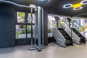 A gym with exercise equipment, a stair machine, and a window with plants. - Cozy 2 BR with Heater,Gym,Pool,ample parking on 3floors at Lavington,Nairobi (Nairobi)