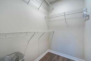 A corner of a room with a wooden floor, white walls, and metal shelving units.