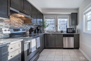 A modern kitchen with dark cabinetry, a stainless steel stove, and a dishwasher.