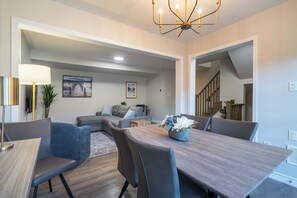 A modern dining area with a wooden table, grey upholstered chairs, and a decorative centerpiece.