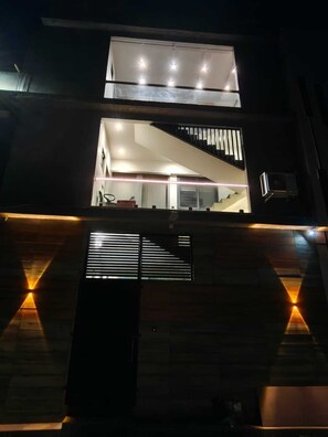 A multi-level building with a staircase, a balcony, and a window with blinds.