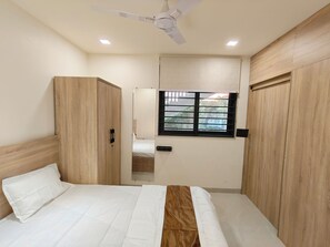 A bedroom with a bed, wardrobe, ceiling fan, and window with blinds.