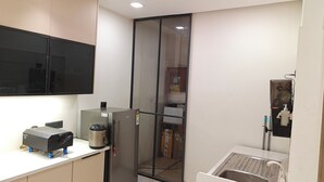 A compact kitchen with a built-in microwave, a refrigerator, and a sink with a faucet. - Peaceful 3 BHK Stay with Premium Amenities (Lucknow)