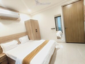 Un dormitori amb llit, armari, ventilador de sostre i finestra amb persianes.