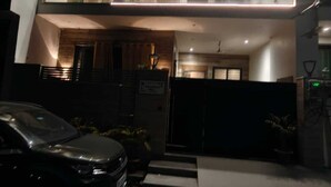 A two-story building with a car parked in front, a gated entrance, and a staircase leading to the entrance. - Peaceful 3 BHK Stay with Premium Amenities (Lucknow)