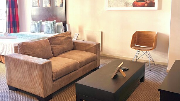 Une chambre d’hôtel moderne avec un canapé, une table basse, un fauteuil et un lit.
