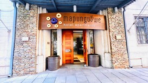 L’entrée d’un hôtel, avec une façade en pierre, une porte en bois et une enseigne au-dessus indiquant « Appartements de l’hôtel Mapungubwe ».