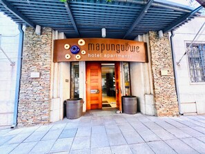 A hotel entrance with a stone facade, a wooden door, and a sign above indicating 'Mapungubwe hotel apartments.' - 1-bedroom apartment in pleasant Johannesburg with WiFi+Pool+Parking (Johannesburg)