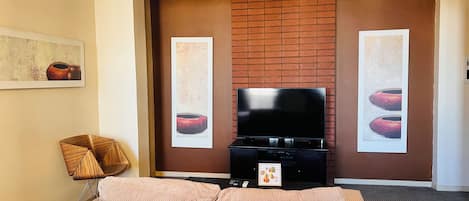 A modern living room with a flat-screen TV, a sofa, and two framed artworks on the wall.