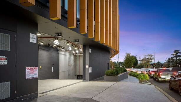 A building entrance with a sign indicating low clearance and a tow away zone. - Austin Hospital | City views | Gym & Pool | 2B1B (Ivanhoe)