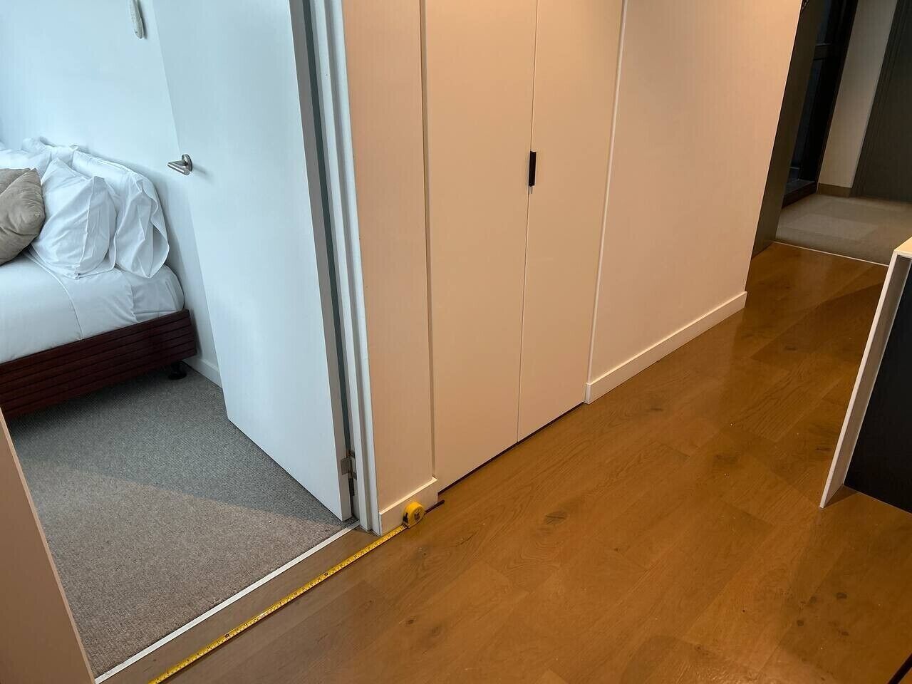 A room with a bed, a white wardrobe, and a wooden floor.