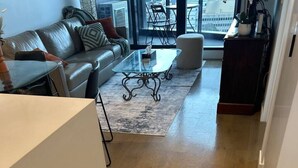 A modern living room with a leather sofa, a glass coffee table, and a wooden floor. - Austin Hospital | City views | Gym & Pool | 2B1B (Ivanhoe)