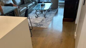 Ein modernes Wohnzimmer mit einer Ledersofa, einem Glastisch und Holzboden.