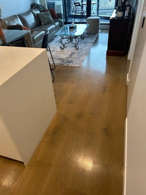 A modern living room with a leather sofa, a glass coffee table, and a wooden floor. - Austin Hospital | City views | Gym & Pool | 2B1B (Ivanhoe)