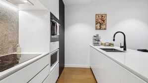 A modern kitchen with white cabinetry, a black faucet, and a wooden floor. - Austin Hospital | City views | Gym & Pool | 2B1B (Ivanhoe)