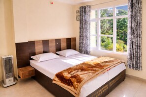 Ein Schlafzimmer mit Bett, einem Fenster mit Vorhängen, einem Heizgerät und einer Wandleuchte.
