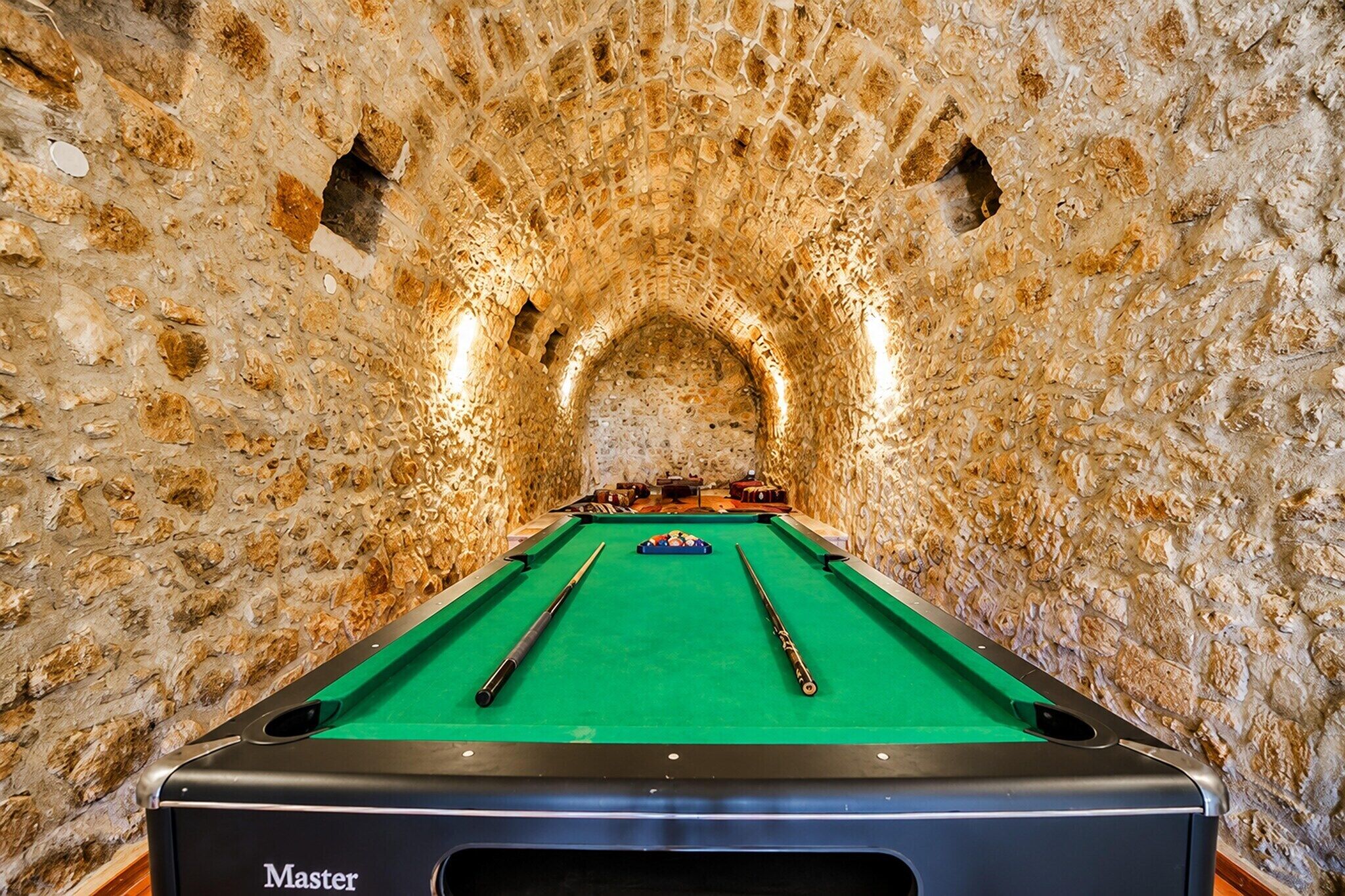 A pool table in a stone-walled room with a green felt surface.