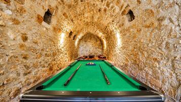 A pool table in a stone-walled room with a green felt surface.