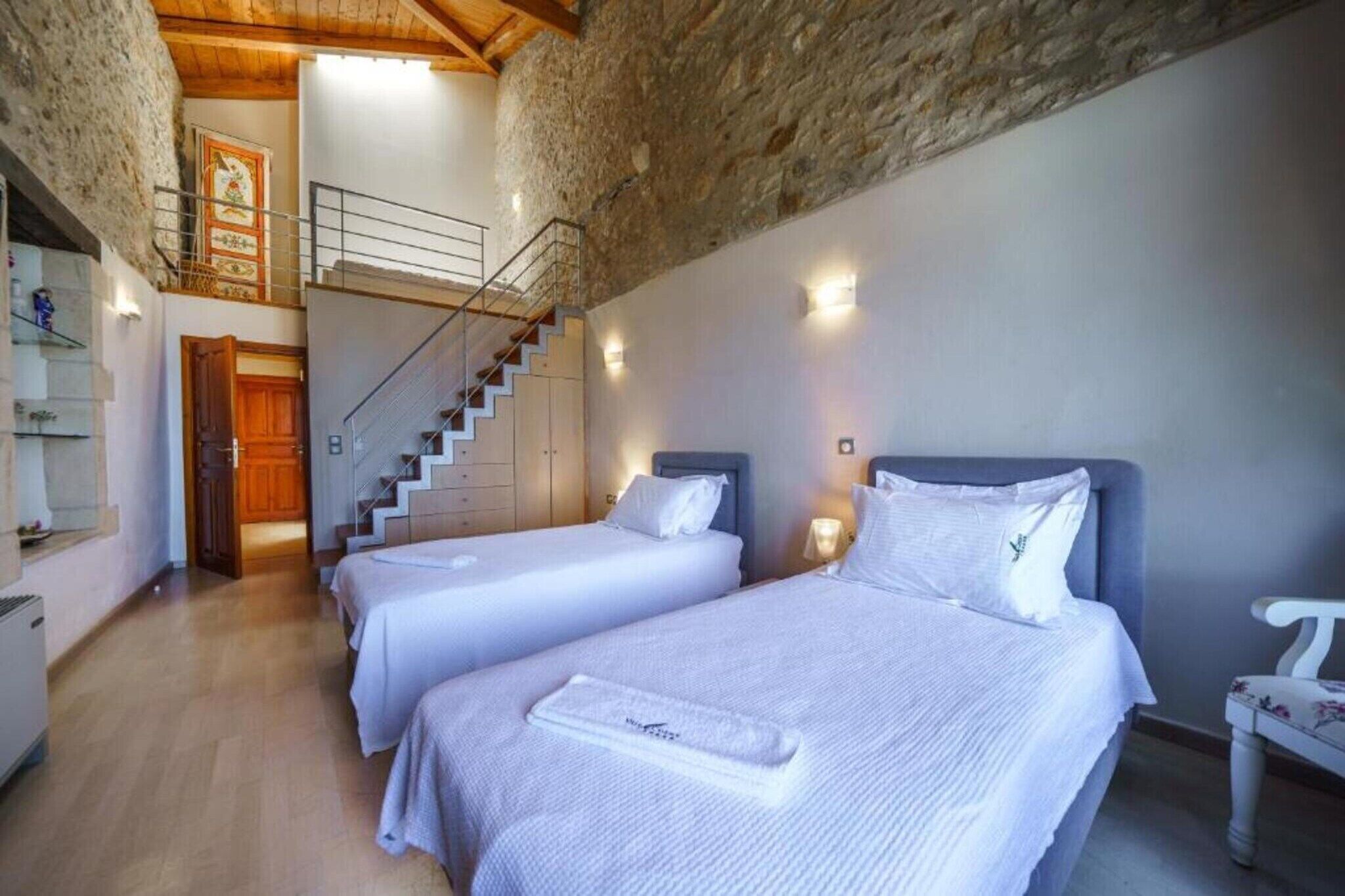 Een hotelkamer met twee bedden, een trap en uitzicht op de bovenverdieping.