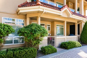 Ein Wohngebäude mit überdachter Veranda, zahlreichen Fenstern und gepflegter Grünanlage.