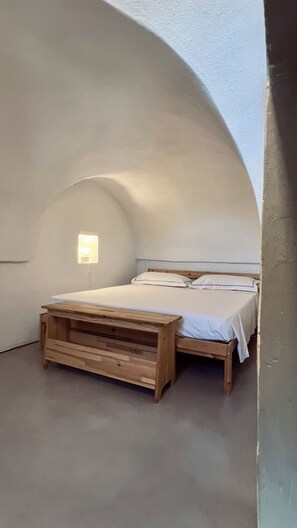 Ein Schlafzimmer mit einem hölzernen Bett, einem Nachttisch und einer Wandleuchte.