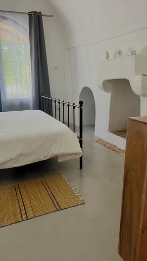 A bedroom with a bed, a window with curtains, a wall-mounted shelf with figurines, and a fireplace. - Le Lamie di Ostuni - a traditional country house with a pool (Puglia)