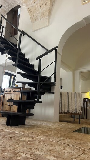 A spiral staircase with a black metal railing in a room with white walls and a stone floor. - Le Lamie di Ostuni - a traditional country house with a pool (Puglia)