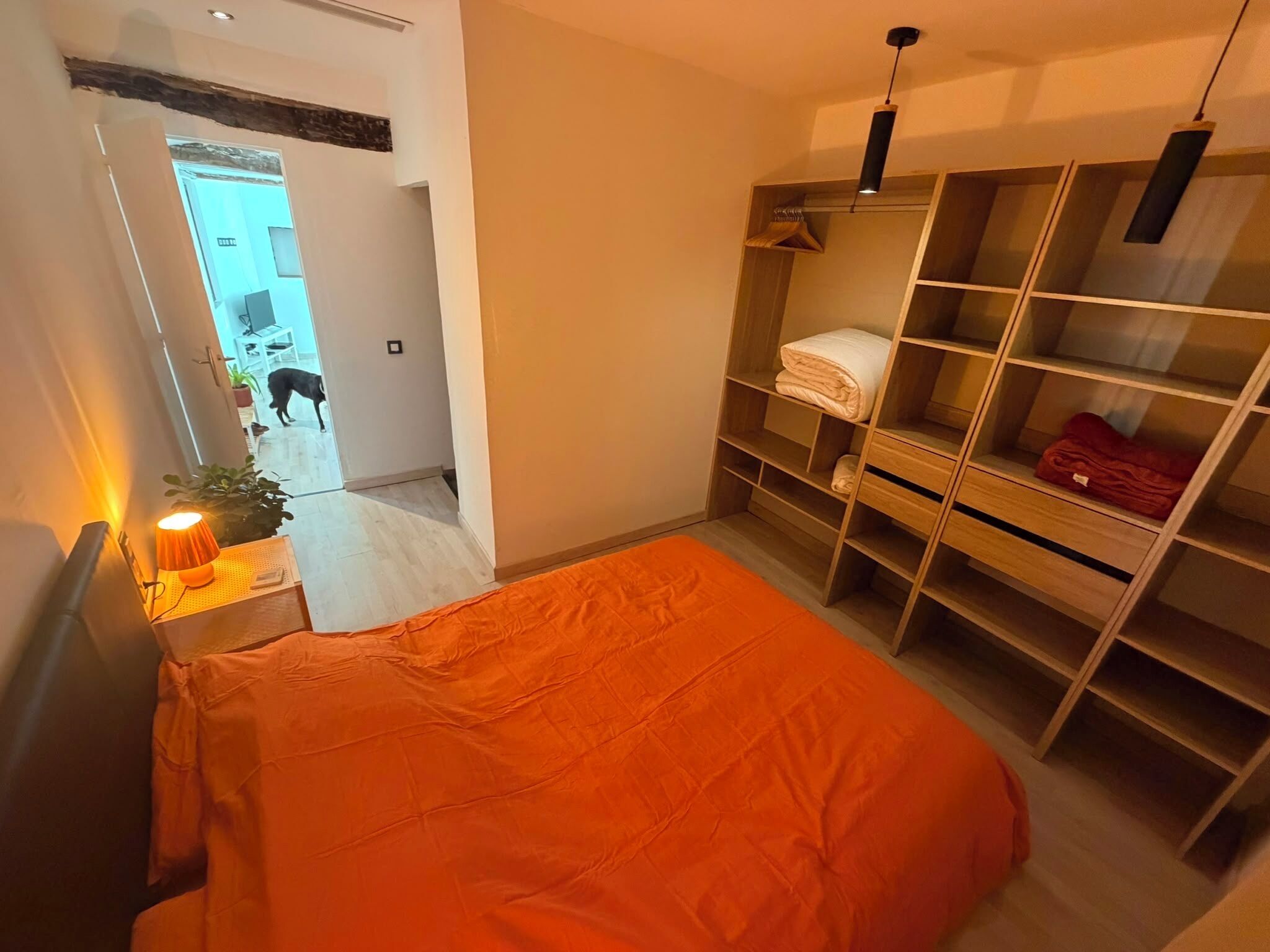 Et moderne soveværelse med seng, et walk-in closet og en gang der fører til et andet rum.
