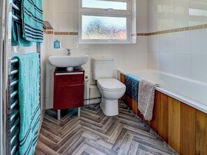 A bathroom with a herringbone floor, a white toilet, a sink, and a bathtub. - 2 bedroom accommodation in Gillingham (Gillingham)