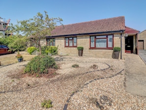 A house with a tiled roof, a front porch with a potted plant, and a gravel driveway. - 2 bedroom accommodation in Gillingham (Gillingham)