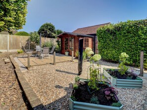 A patio area with outdoor furniture, a wooden fence, and a small garden with raised beds. - 2 bedroom accommodation in Gillingham (Gillingham)