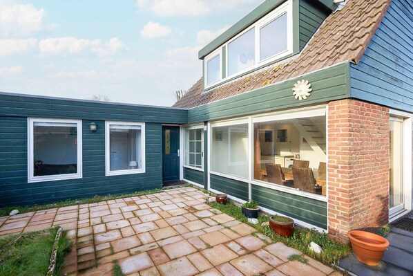 Une maison à deux étages, avec une façade en briques et un toit recouvert de tuiles.