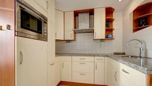 A compact kitchen with a built-in oven, a sink, and wooden cabinets. - Holiday Home in South Holland (Noordwijkerhout)