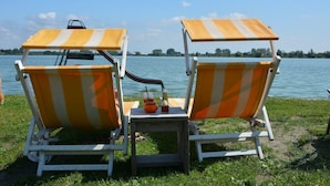 Two beach chairs with striped canopies facing a lake. - Holiday Home in South Holland (Noordwijkerhout)