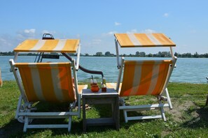 Two beach chairs with striped canopies facing a lake. - Holiday Home in South Holland (Noordwijkerhout)