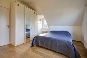 Une chambre à coucher avec un lit, une armoire et une fenêtre.