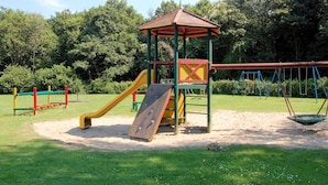 A playground with a slide, swings, and a climbing structure. - Holiday Home in South Holland (Noordwijkerhout)