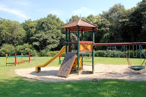 A playground with a slide, swings, and a climbing structure. - Holiday Home in South Holland (Noordwijkerhout)