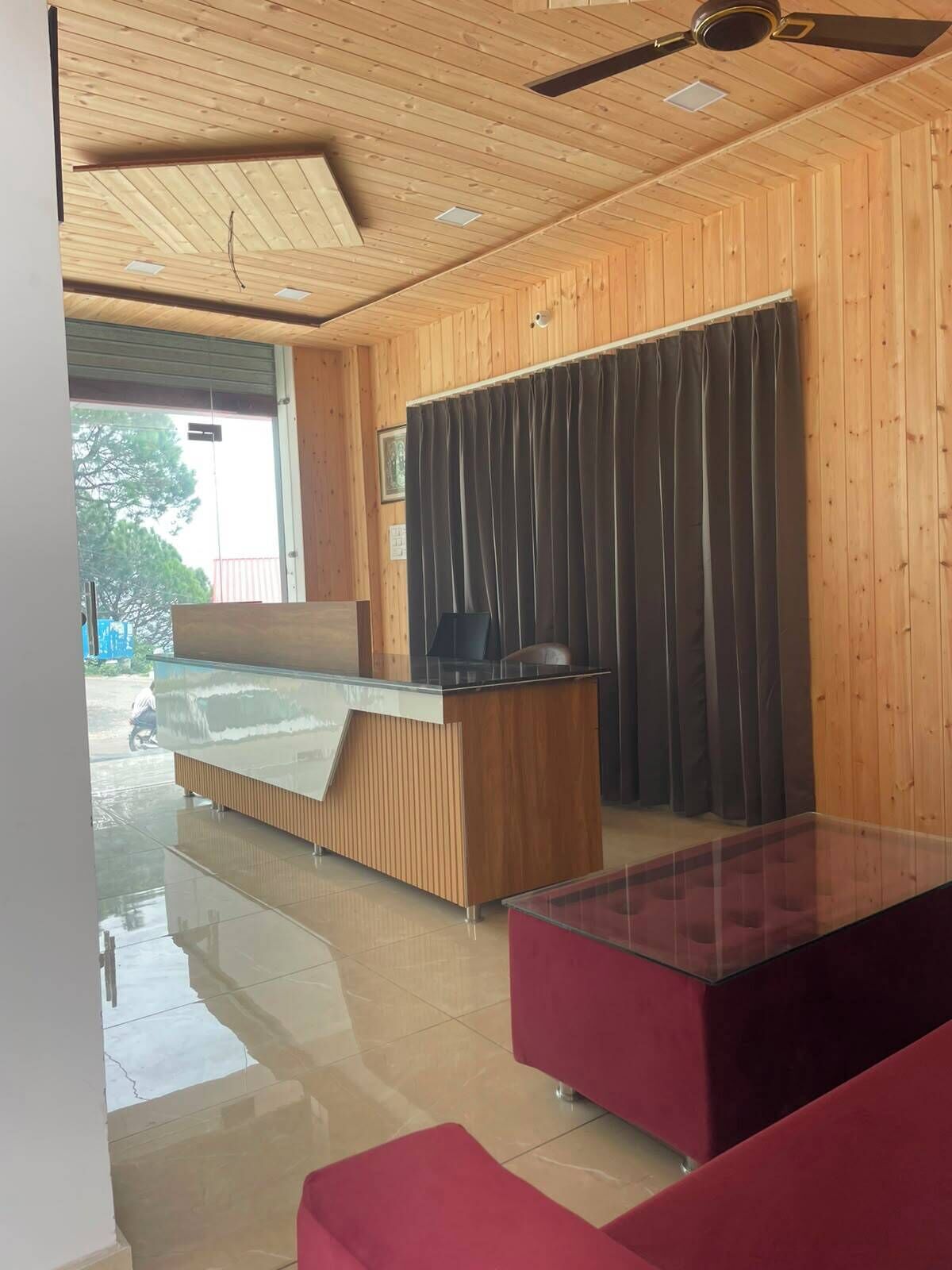Habitación de hotel con techo de madera, cama con cabecera de madera, escritorio, una silla y un sofá rojo.