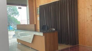 Habitación de hotel con techo de madera, cama con cabecera de madera, escritorio, una silla y un sofá rojo.