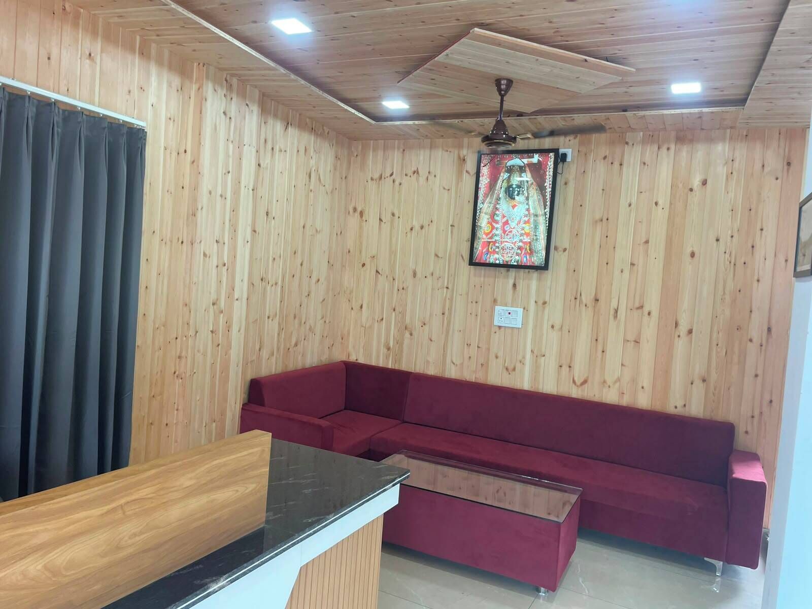 Ein Zimmer mit Holzvertäfelung, einem roten Sofa, einem Holztisch und einem Deckenventilator.