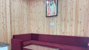 Una habitación con un panel de madera, un sofá rojo y una mesa de centro de vidrio.