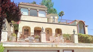 Una casa de dos pisos con balcón, ventanas arqueadas y garaje.