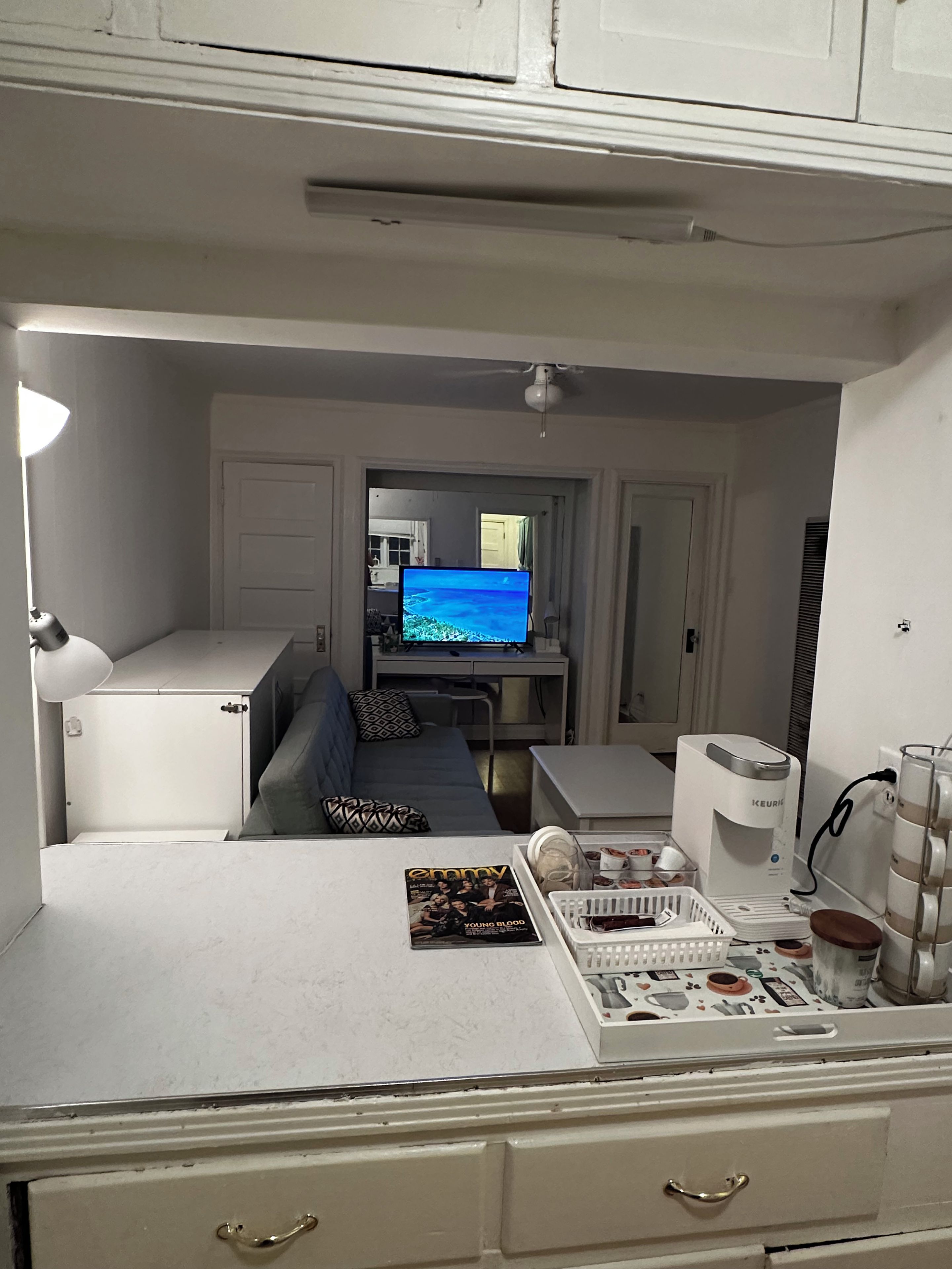A compact living space with a kitchenette, a sofa, a television, and a coffee maker.