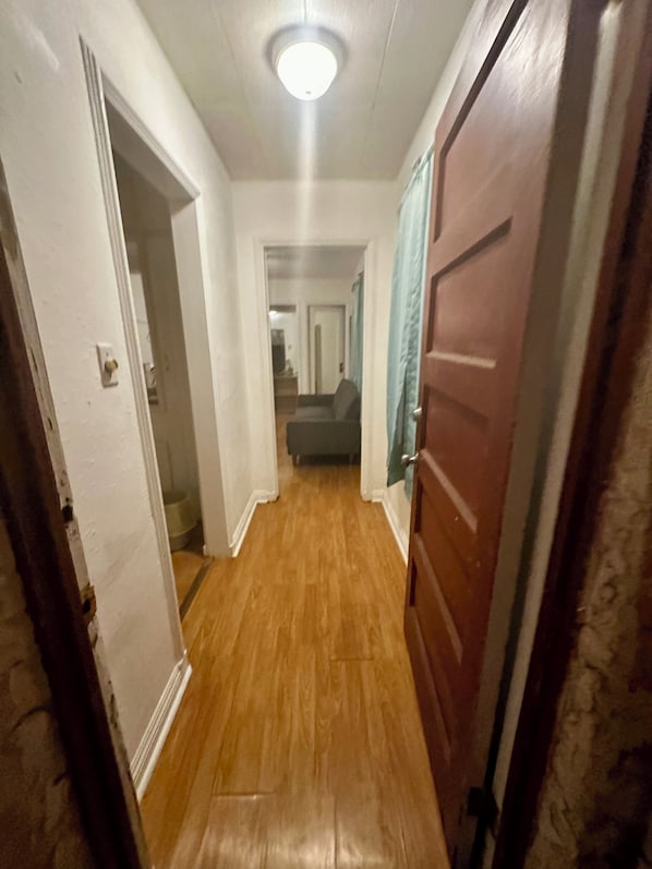 A hallway with wooden flooring, white walls, and a ceiling light.
