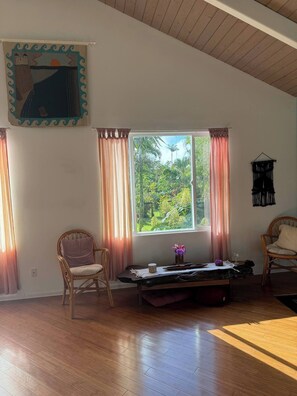 Une pièce comprenant un lit, deux chaises, une table et une fenêtre avec des rideaux.