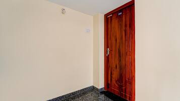 A hallway with a wooden door marked '202' and a light switch on the wall.